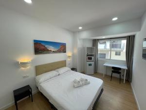 a bedroom with a white bed and a desk at Lux Hostal in Hospitalet de Llobregat
