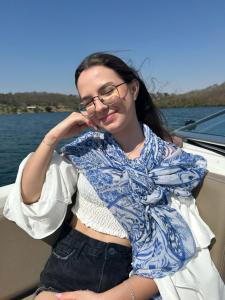 Una mujer con gafas sentada en un barco. en Flamboyant Boat, en Ubatuba