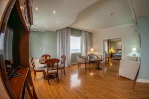 una sala de estar con mesa y sillas y una habitación en Lucania Palazzo Hotel, en Comodoro Rivadavia
