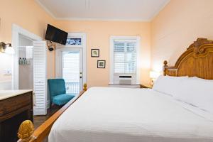 een slaapkamer met een groot bed en een blauwe stoel bij Curry House Room 6 in Key West