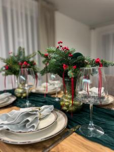 einen Tisch mit Tellern, Weingläsern und Weihnachtsdekorationen in der Unterkunft Saulės Tako apartamentai in Druskininkai