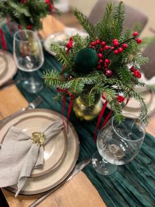 ein Tisch mit Tellern und eine Vase mit Weihnachtsdekorationen in der Unterkunft Saulės Tako apartamentai in Druskininkai