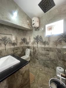 a bathroom with a sink and a toilet and trees on the wall at IndivaStays - Moon Stone Villa in Ooty +21 photos