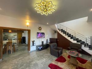 a living room with a staircase and a chandelier at IndivaStays - Moon Stone Villa in Ooty