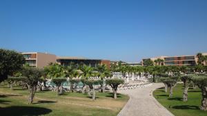 a path through a park with palm trees and a building at Herdade dos Salgados - Vila das Lagoas - Private Apartaments in Albufeira