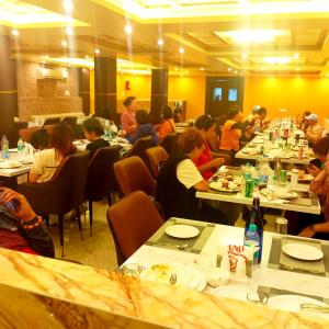 un grupo de personas sentadas en mesas en un restaurante en Hotel Royal - View - Residency & Restaurant Bodh Gaya Near Temple & The Great Buddha Statue Fully Air Conditioning Rooms- Premium Quality Hotel Inn Bodh Gaya, en Bodh Gaya