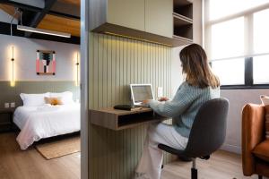 a woman sitting at a desk with a laptop in a bedroom at Outsite Mexico City Roma Sur - Work, Connect, Explore in Mexico City