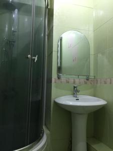 y baño con lavabo y ducha con espejo. en Bishkek Apartment Central, en Bishkek