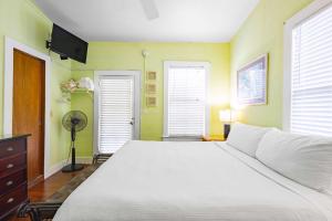 a bedroom with a white bed and two windows at Curry House - Pool, King Bed & Balcony! Room 7 in Key West