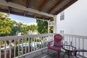 a porch with a red chair and a table at Curry House - Pool, King Bed & Balcony! Room 7 in Key West