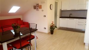 een keuken en een woonkamer met een tafel en een rode bank bij Mansardina in Sanremo +2 foto's