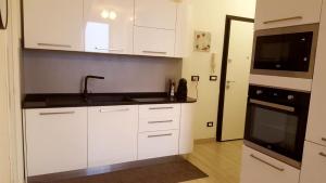 een keuken met witte kasten, een spoelbak en een magnetron bij Mansardina in Sanremo