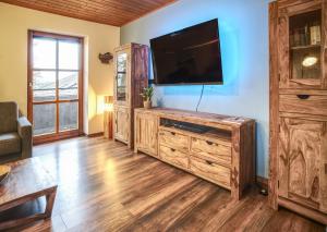 sala de estar con TV de pantalla plana en un centro de entretenimiento de madera en Ferienwohnung Freudensee im Bayerischen Wald - Pool, Sauna, en Hauzenberg