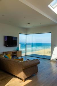 een woonkamer met een bank en een groot raam bij Ocean Skies in Porthtowan
