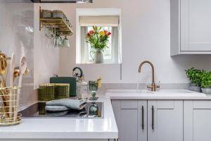 a kitchen with white cabinets and a sink and a window at Birch Studio in Camborne +30 photos