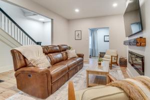 a living room with a brown leather couch and a fireplace at Game Room and Backyard Modern Altoona Home! in Altoona
