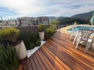 una terraza con mesa, sillas y piscina en Chalé Requinte da Serra, en Miguel Pereira