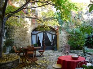 patio con tavolo e sedie sotto un muro di pietra di Au Fil Des 5 Saisons a Vers-Pont-du-Gard