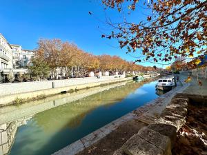 a river with boats on it in a city at Charmant deux pièces en plein centre-ville de NARBONNE in Narbonne
