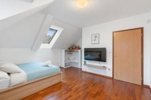 een slaapkamer met een bed en een flatscreen-tv bij The Dante House Šeberov in Praag