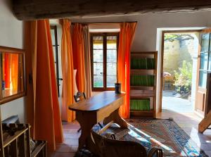 una stanza con un tavolo di legno e tende arancioni di Au Fil Des 5 Saisons a Vers-Pont-du-Gard