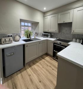 a kitchen with white cabinets and a wooden floor at 1 Gilmore Close in Alston