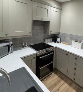a kitchen with white cabinets and a stove top oven at 1 Gilmore Close in Alston