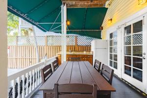 une table en bois sur une véranda avec des chaises et un réfrigérateur dans l'établissement Curry House - Room 9, à Key West 5 autres photos