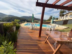 a wooden deck with a table and chairs next to a pool at Suite Requinte da Serra in Miguel Pereira