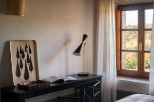 a bedroom with a desk with a lamp and a window at Fattoria di Vegi in Castellina in Chianti +53 photos