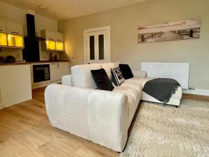 a white couch in a living room with a kitchen at The Nairn Neuk - Couples Cosy Getaway in Nairn