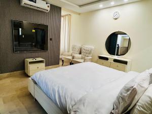 a bedroom with a bed and a mirror and a tv at OSMA Residency in Islamabad
