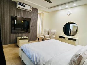 a bedroom with a bed and a mirror and a tv at OSMA Residency in Islamabad