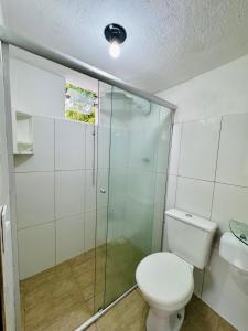 a bathroom with a toilet and a glass shower at Mandacaru Pousada in Porto Seguro