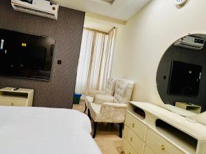 a hotel room with a bed and a chair and a mirror at OSMA Residency in Islamabad