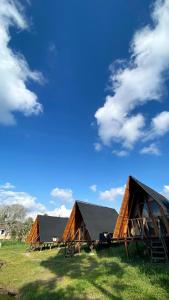 two barns on a grass field with a blue sky at Lago Cristal Chalets in Bucaramanga