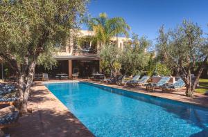 a swimming pool with chairs and trees and a building at Boutique Hotel Katia in El Harkat