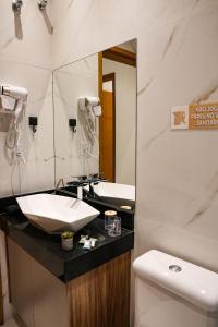 a bathroom with a sink and a toilet and a mirror at Home Aguas da barra Ilhabela in Ilhabela