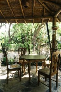 einen Holztisch und Stühle unter einem Holzdach in der Unterkunft Beautiful house in Guasacate 100 meters from the sea in Popoyo