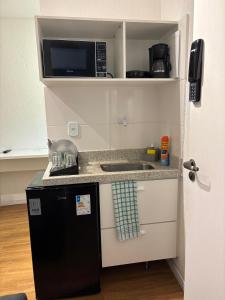 a small kitchen with a sink and a microwave at 100 m da Praia do Forte com AR e Wi Fi in Cabo Frio