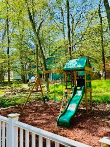 a playground with a green slide in a yard at Lakeview Family Retreat Newly Renovated 4BR House in Pocono Country Place