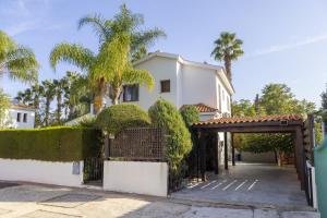 een wit huis met een poort en palmbomen bij Relax Villa in Lachi