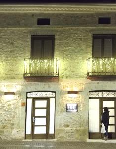 a person standing in front of a building with two windows at Apartamentos LA CAÑADA DE OSMA in El Burgo de Osma