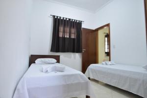 1 Schlafzimmer mit 2 Betten mit weißer Bettwäsche und einem Spiegel in der Unterkunft Casa Familiar Morada in Aparecida