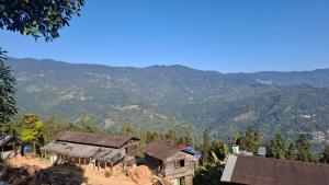 a group of houses with mountains in the background at Cinchonna Farmstay in Darjeeling +18 photos