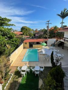 una piscina con mesas y sillas junto a una casa en Pousada Alto Mar Saquarema, en Saquarema