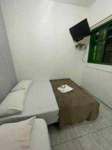 una pequeña habitación con una cama y una mesa en Pousada Alto Mar Saquarema, en Saquarema