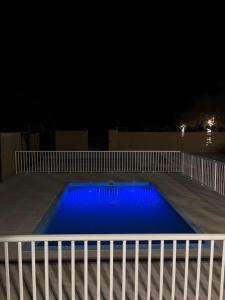a blue swimming pool at night with a white fence at Alawadhi Farm 1 in Ras al Khaimah