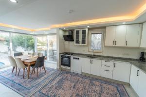 kuchnia z białymi szafkami i stołem z krzesłami w obiekcie Villa Sena w mieście Dalyan