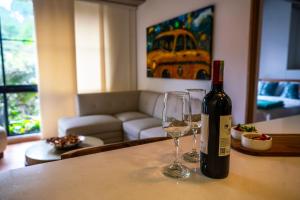 a bottle of wine and two glasses on a table at Home away from home - By Adri in Envigado